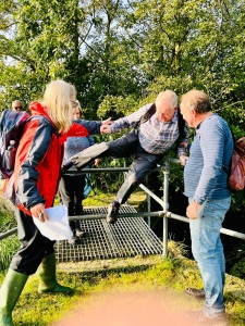 Man climbing fence with people helping